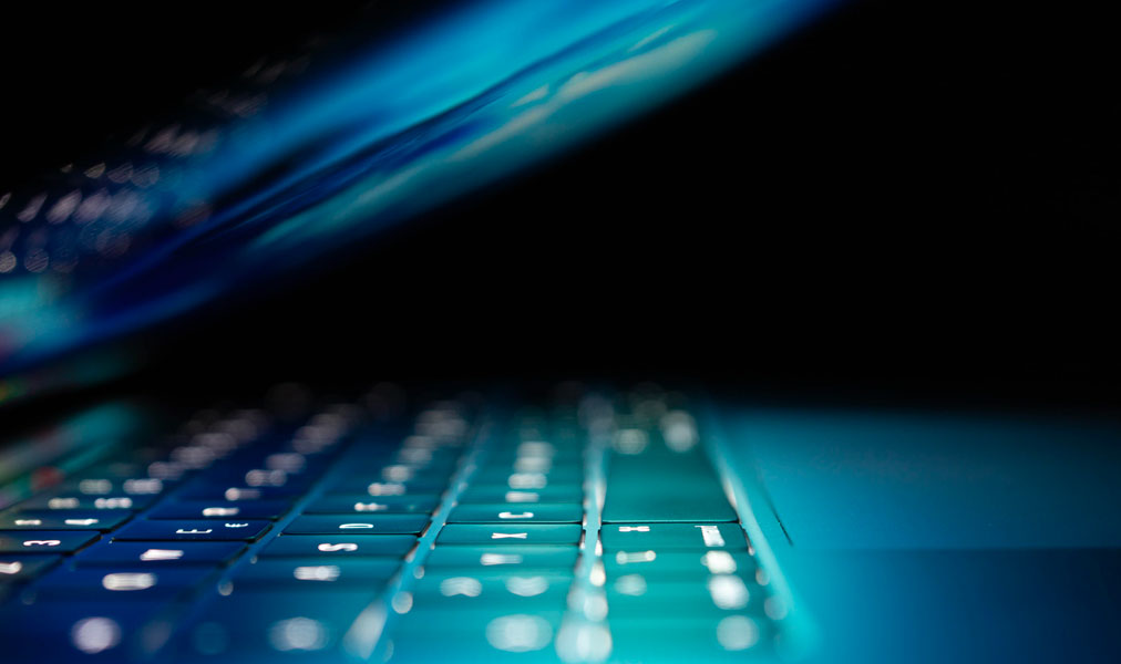 Laptop partially closed with blue low lighting